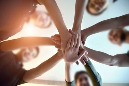 A group of people are putting their hands together in a circle.