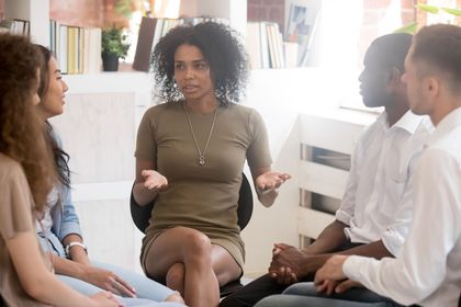 A group of people are sitting in a circle talking to each other.