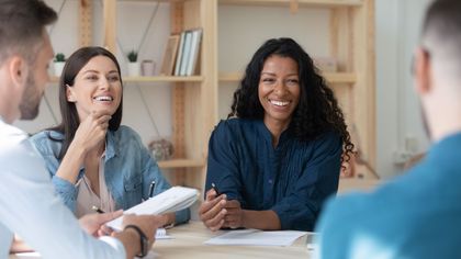 A group of people are sitting around a table having a meeting.