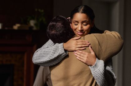 A woman is hugging a man in a living room.
