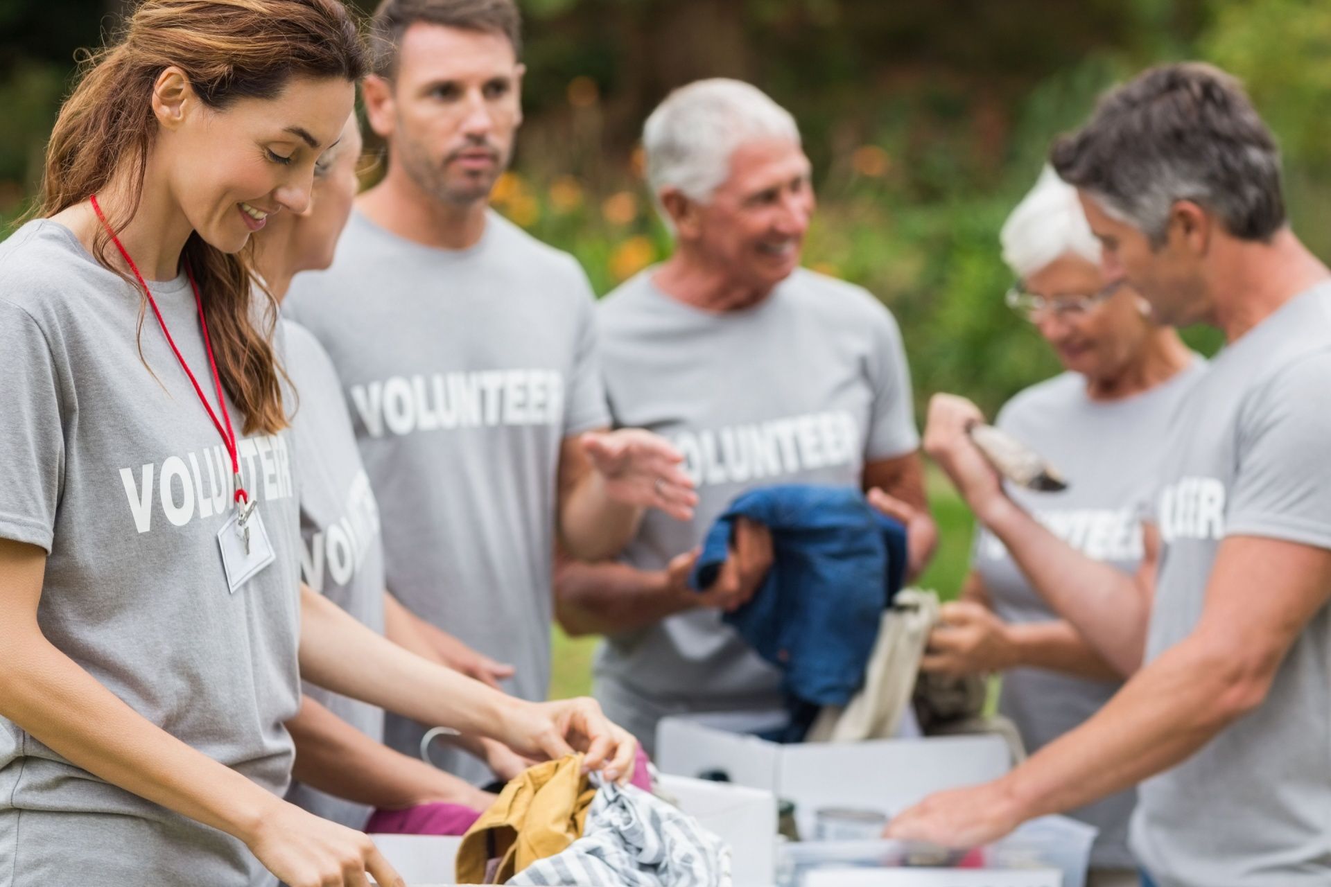 A group of volunteers are sorting clothes in a park.