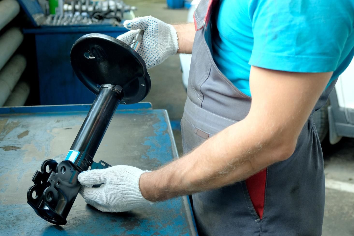 A Man is Holding a Shock Absorber in His Hands — Strut Re-gas Mackay In Ooralea, QLD