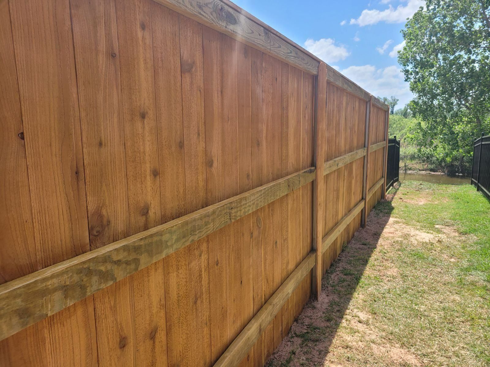 A wooden fence is sitting in the middle of a lush green field.