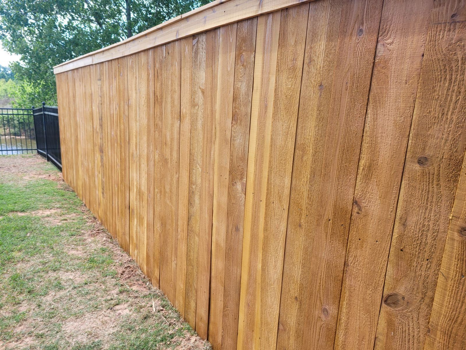 A wooden fence is sitting on top of a lush green field.