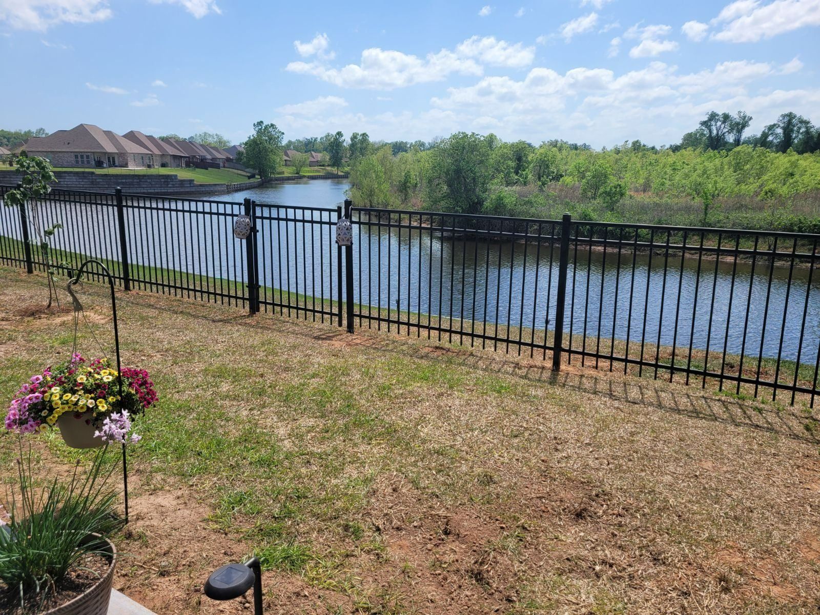 A fence surrounds a yard with a river in the background.