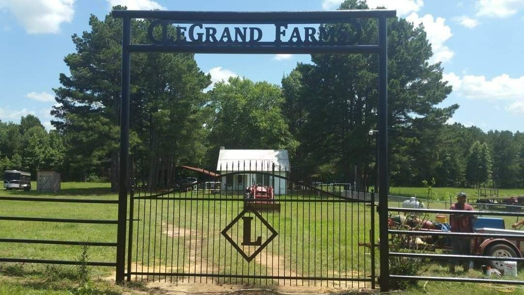 A gate with a sign that says grand farm on it