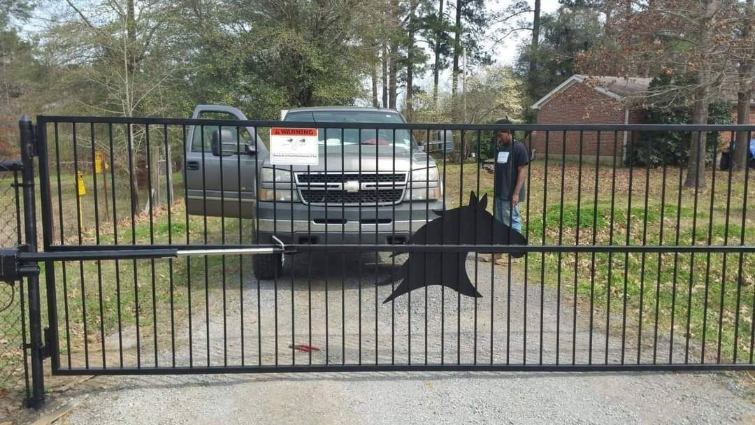 A man is standing behind a gate with a picture of a horse on it.
