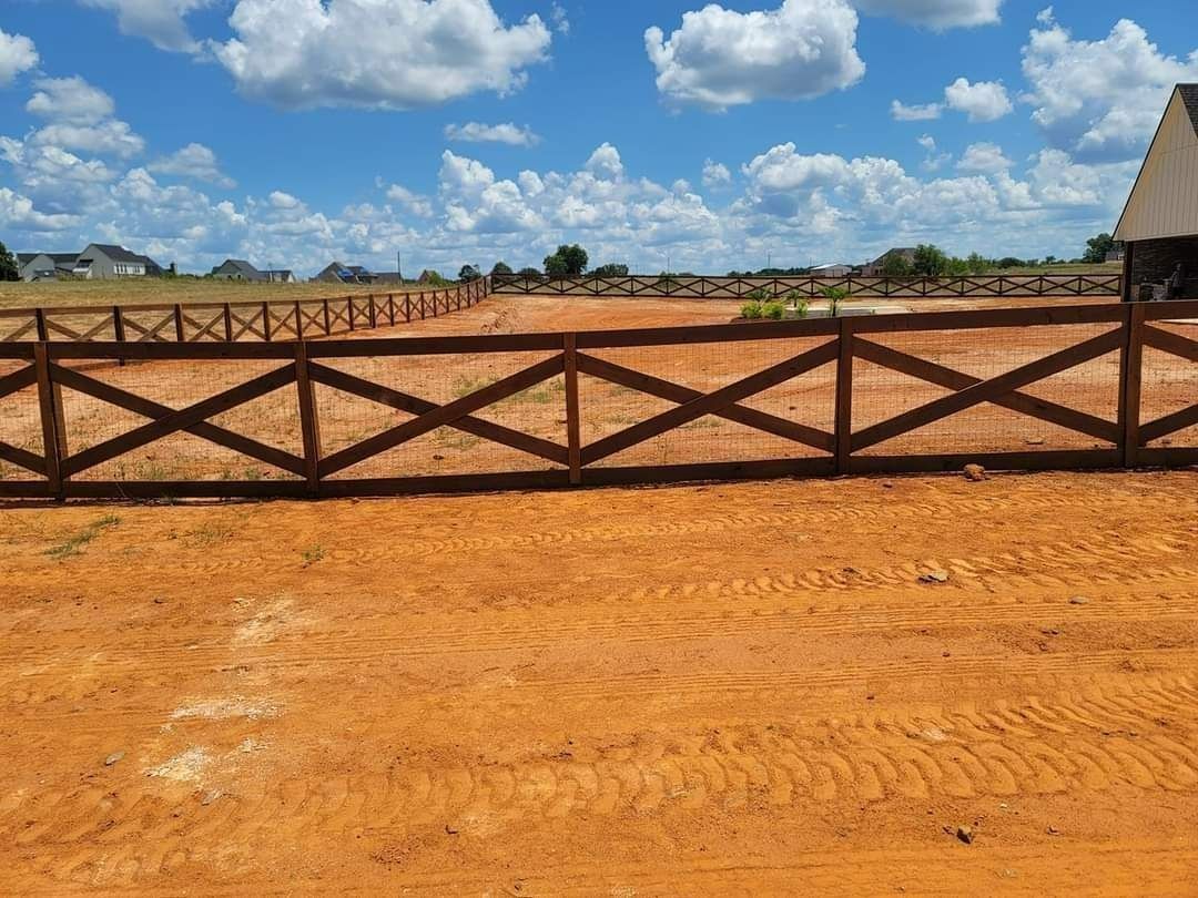 A wooden fence is sitting in the middle of a dirt field.