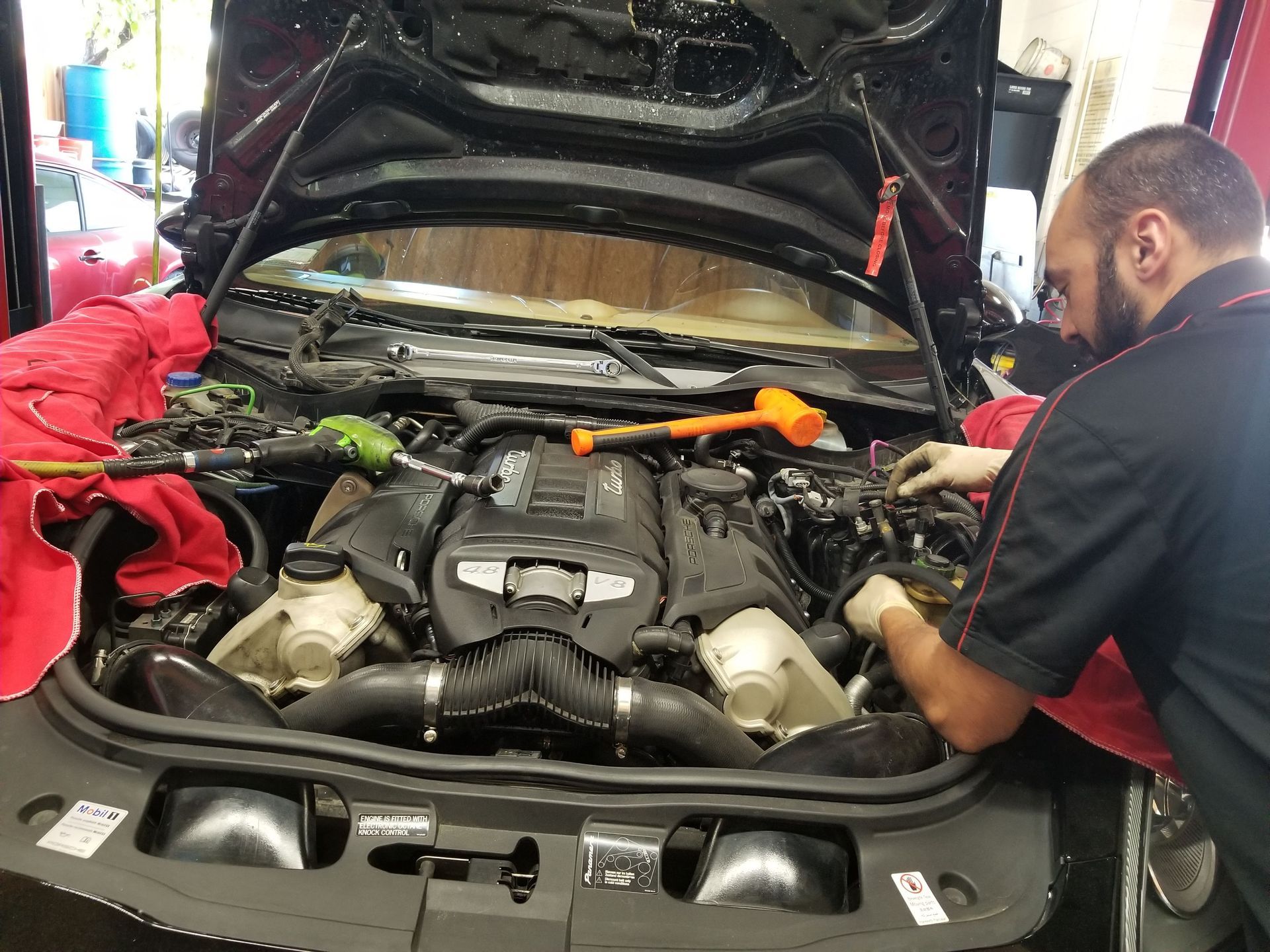 Mechanic working on a black car engine | Koncept Motorwerks