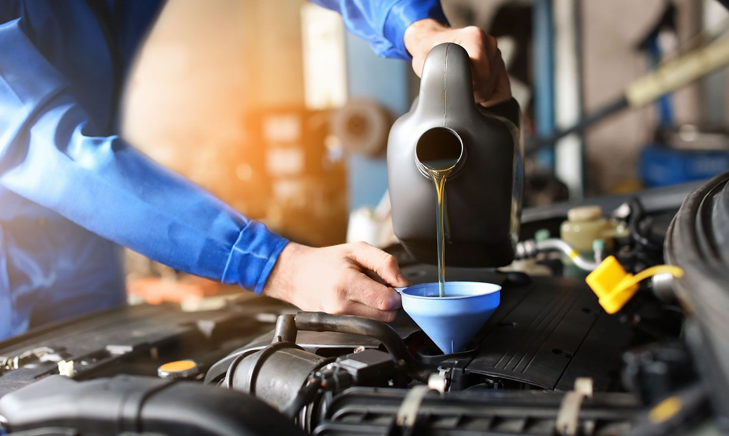 A mechanic is pouring oil into a car engine.
