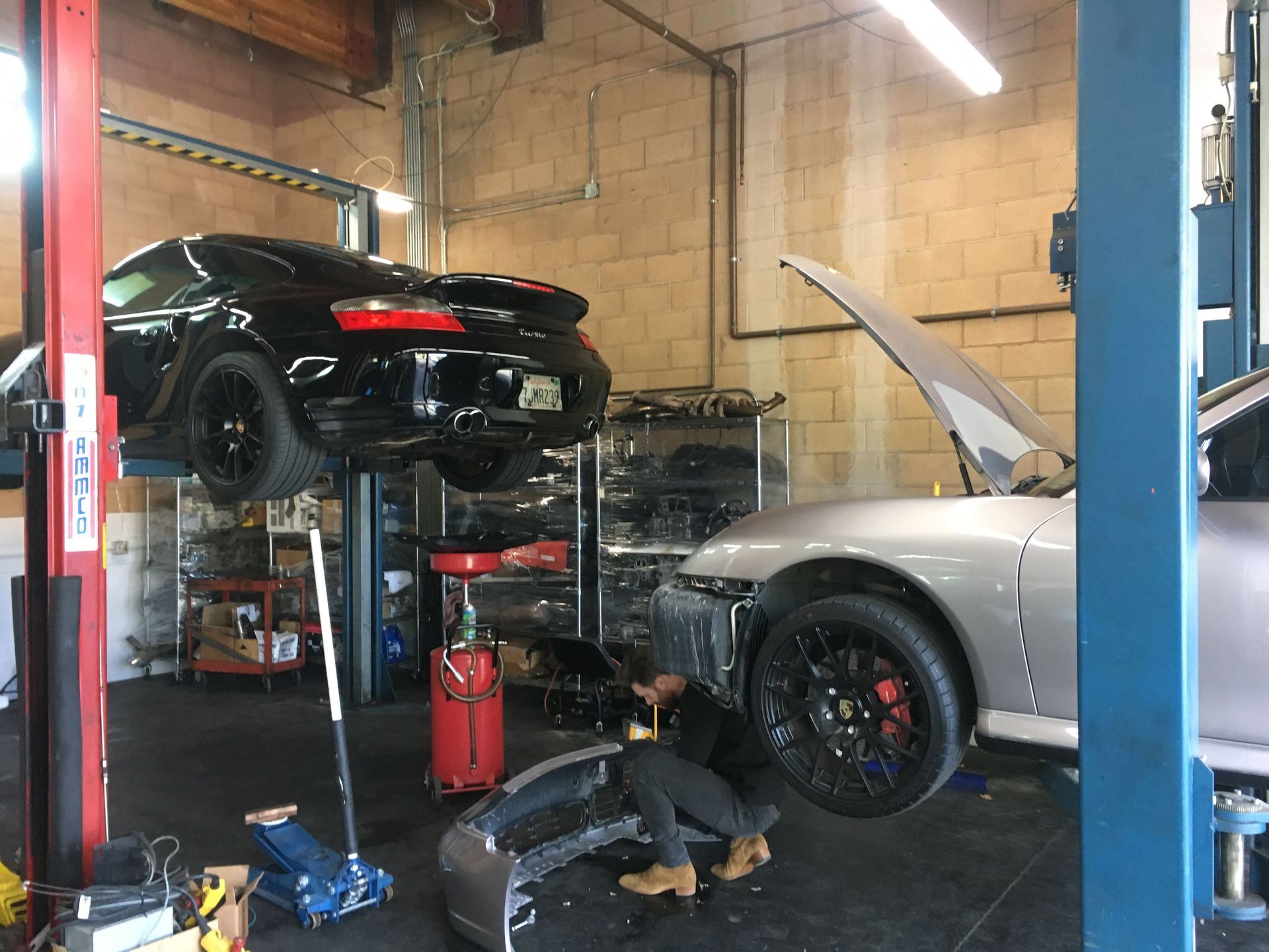 Mechanic works on two sports cars in a garage | Koncept Motorwerks