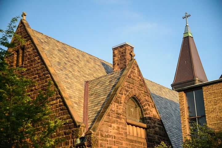 A brick church with a steeple and a cross on top of it.