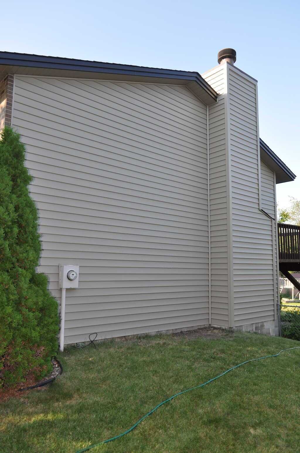 The side of a house with a chimney on top of it.