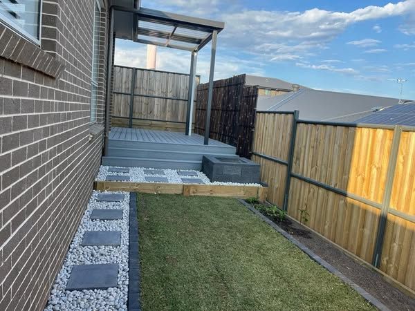 A brick building with a wooden fence and a lawn in front of it.