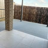 A patio with a brick pillar and a bamboo fence in the background.