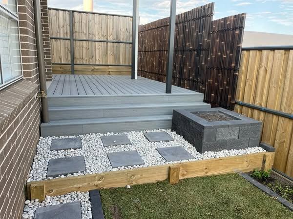 A deck with stairs and a fire pit in the backyard of a house.