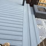A dog is sitting on a wooden deck next to a fire pit.