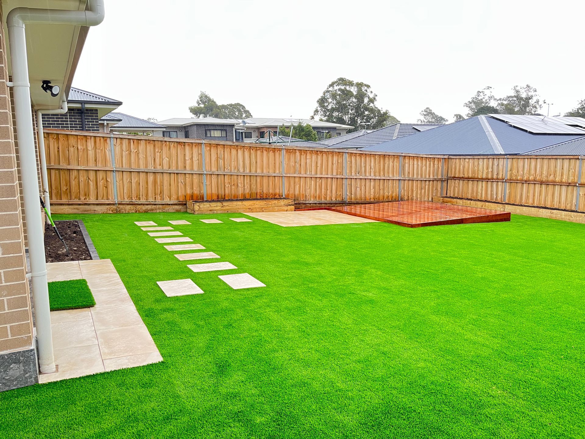 A backyard with a wooden fence and a lush green lawn.