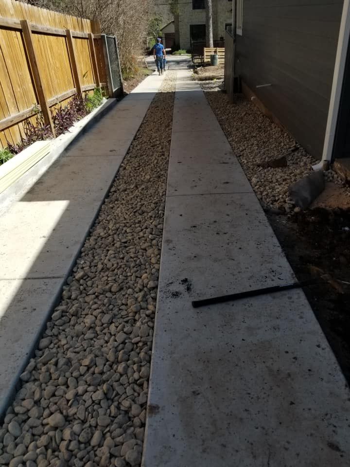 A person is walking down a sidewalk next to a fence.