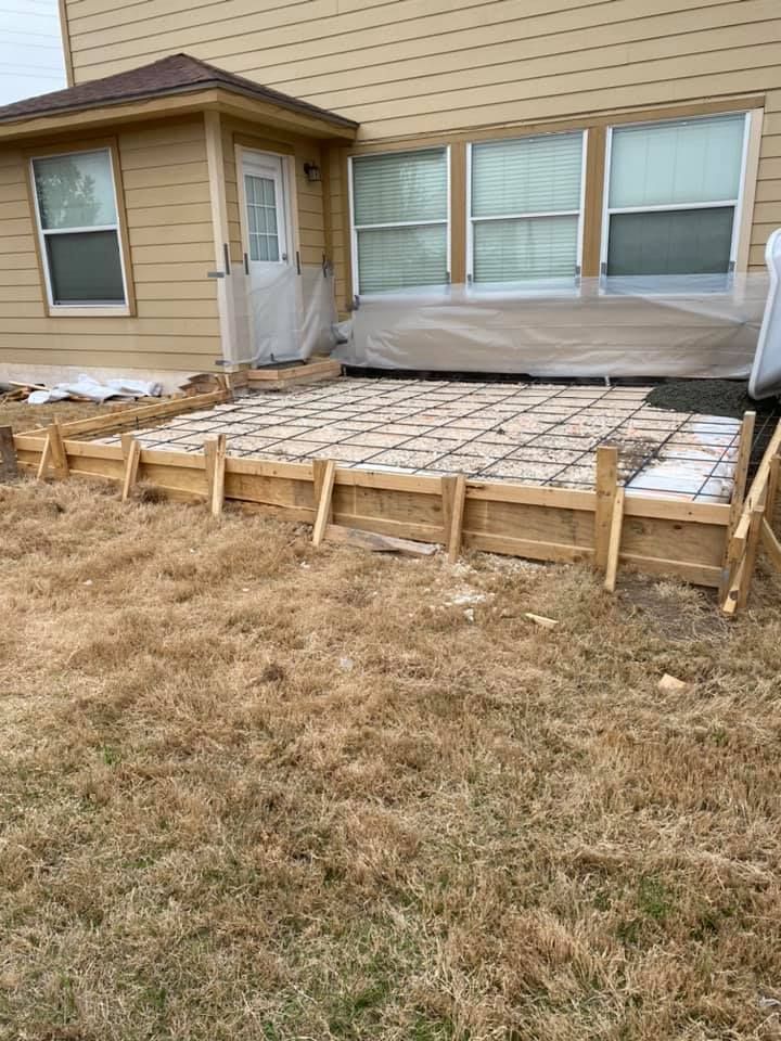 A concrete patio is being built in front of a house.