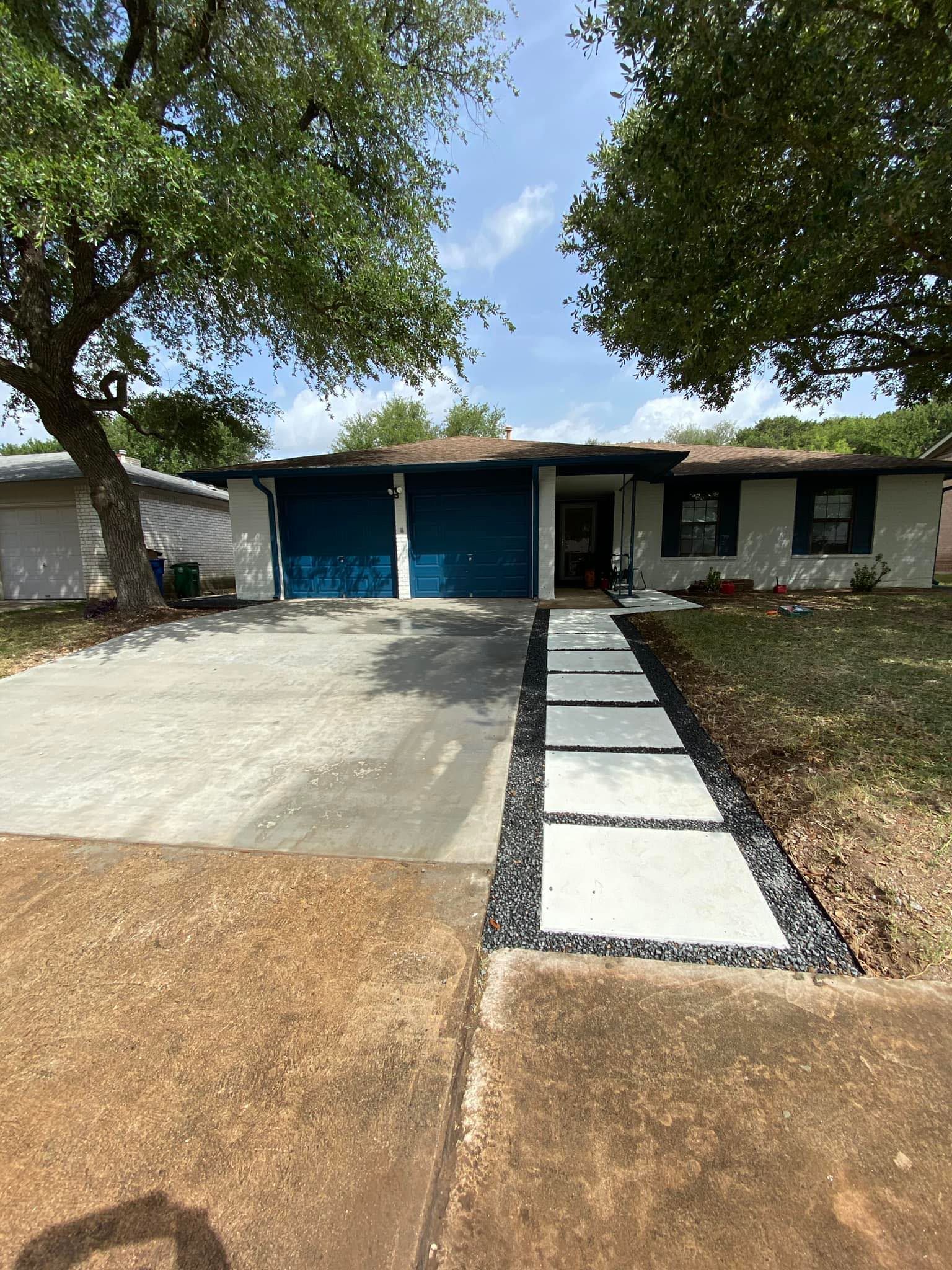 A house with a blue garage door and a walkway leading to it.