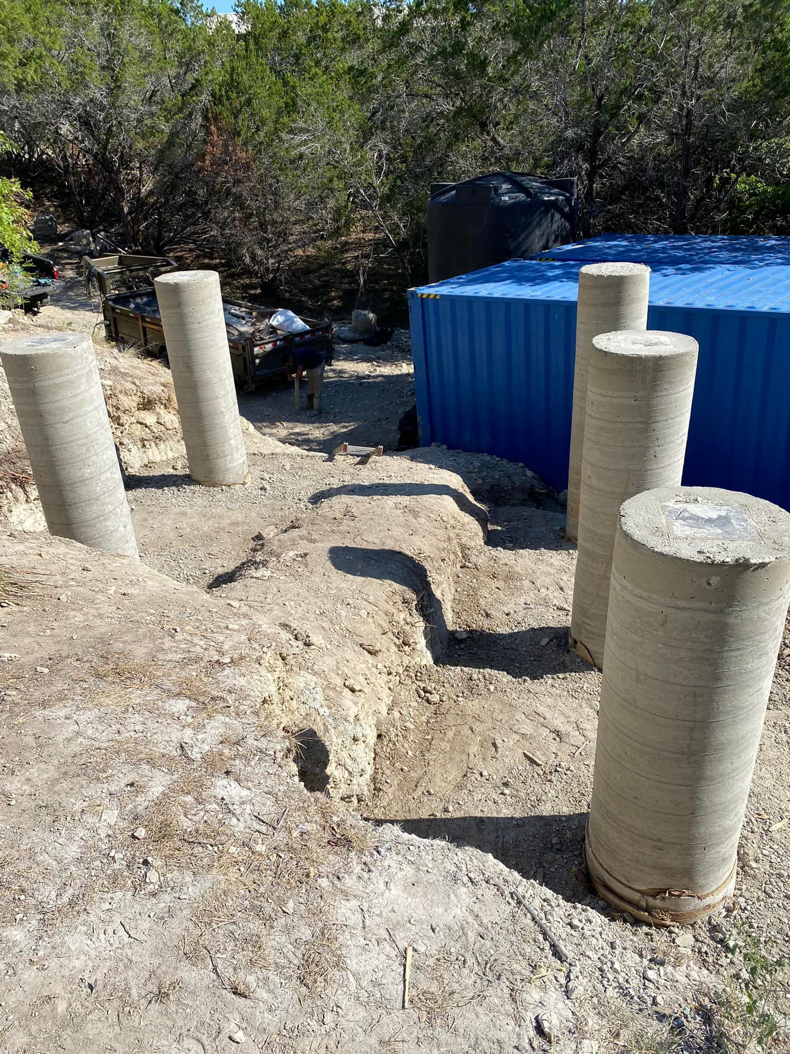 A group of concrete pillars sitting on top of a dirt field.