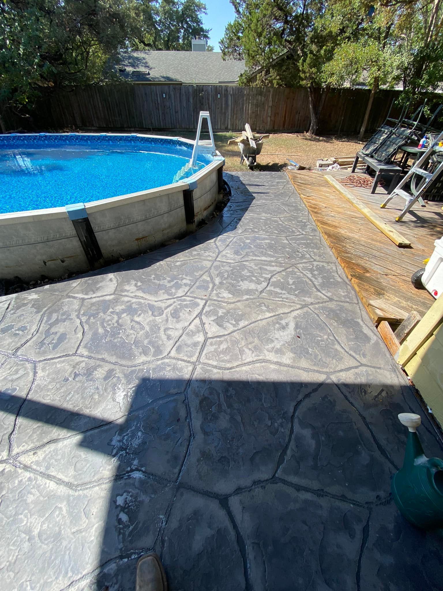 A swimming pool is sitting on top of a concrete patio in a backyard.