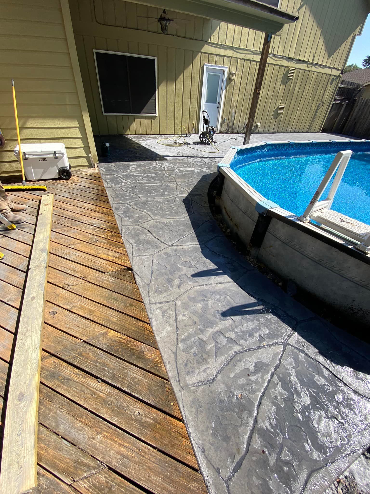 A swimming pool is sitting next to a wooden deck.