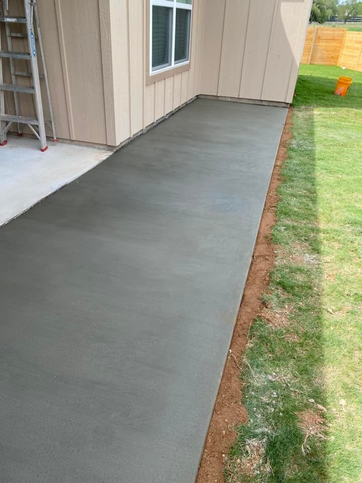 A concrete walkway leading to a house with a ladder in the background.