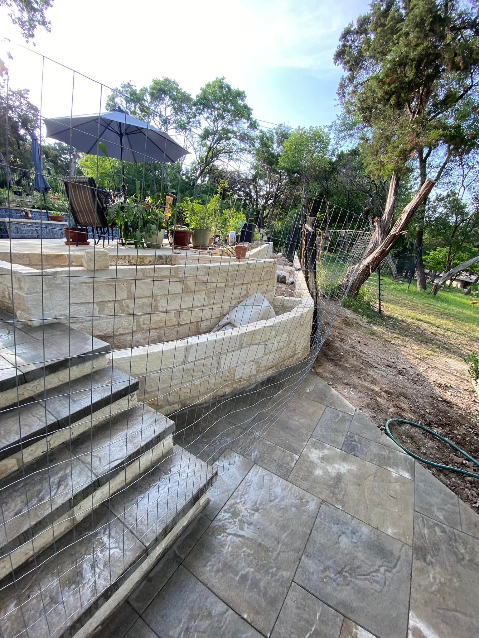A patio with stairs leading up to a brick wall and umbrellas.