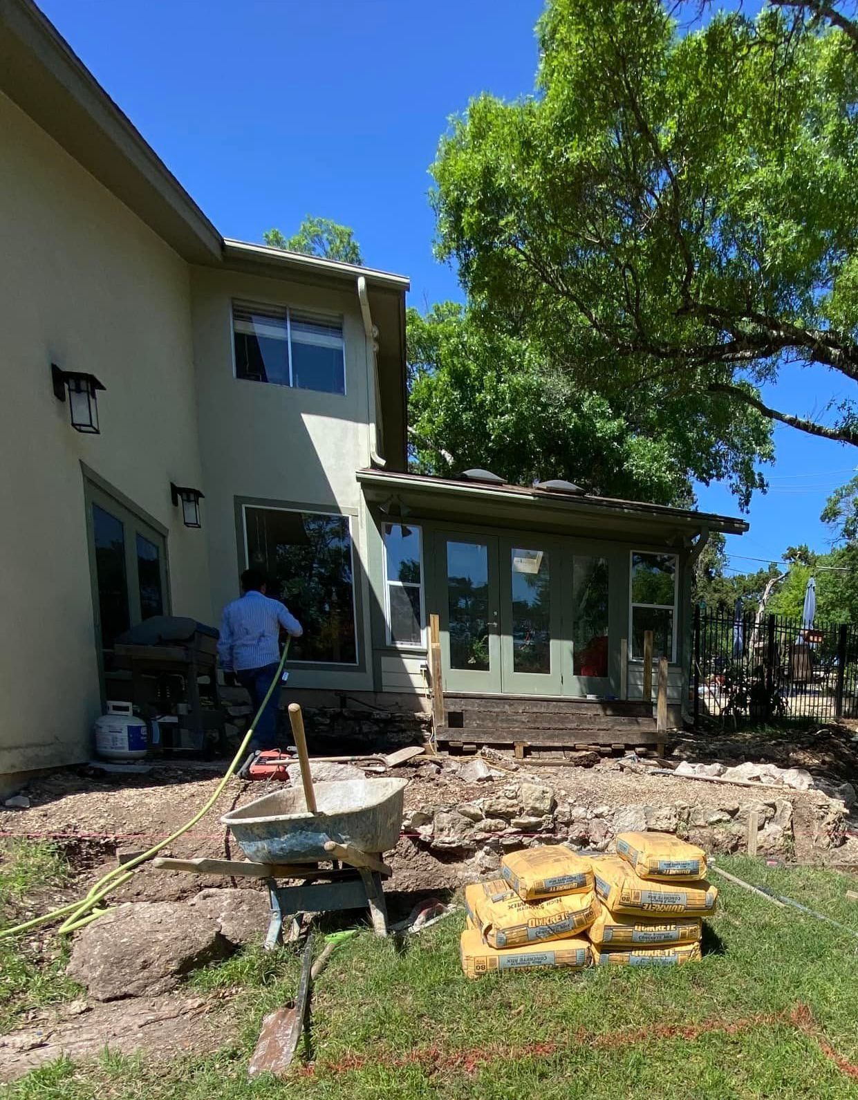 A man is working on a patio in front of a house.