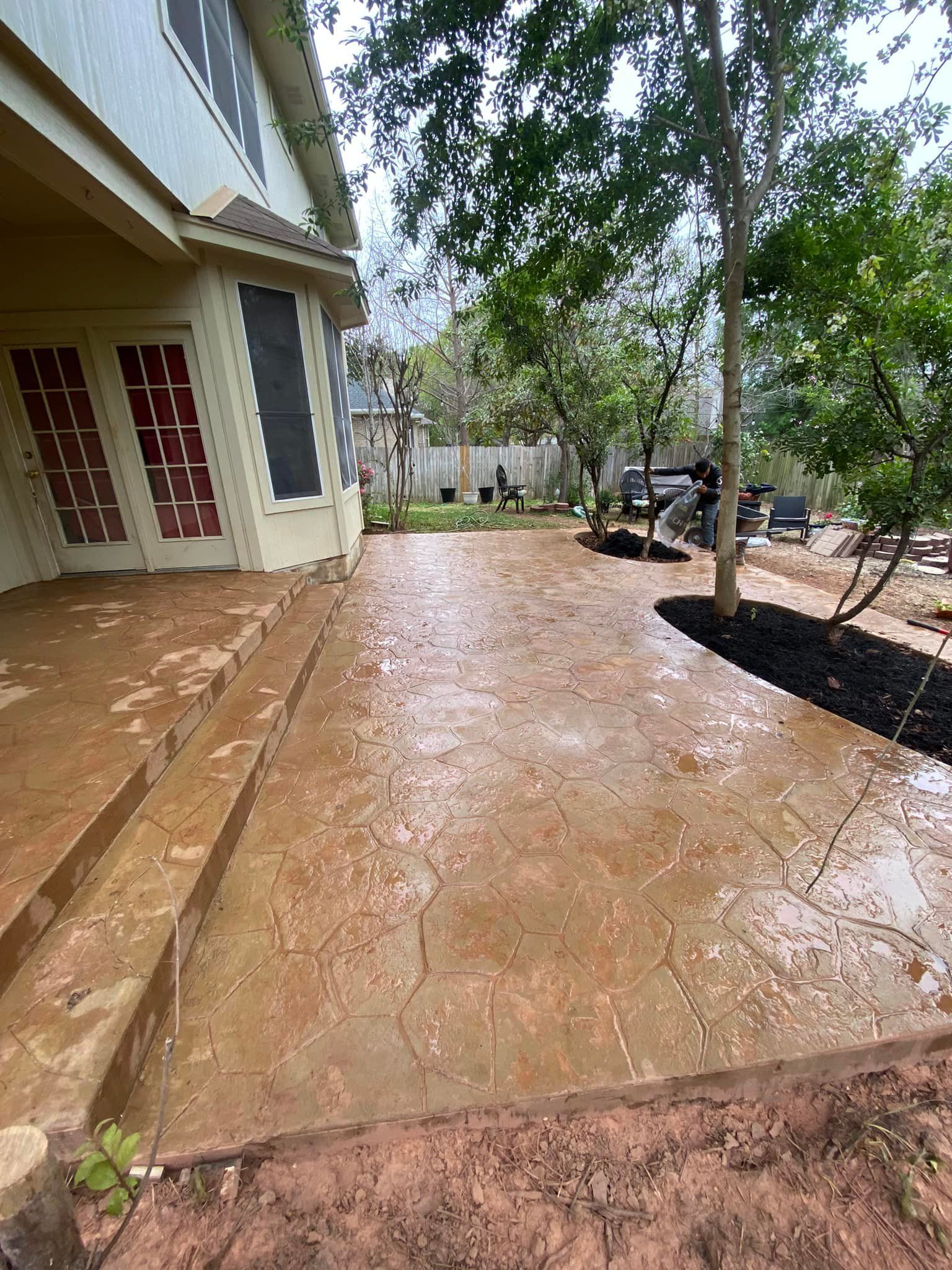 A concrete patio in front of a house with trees in the background.