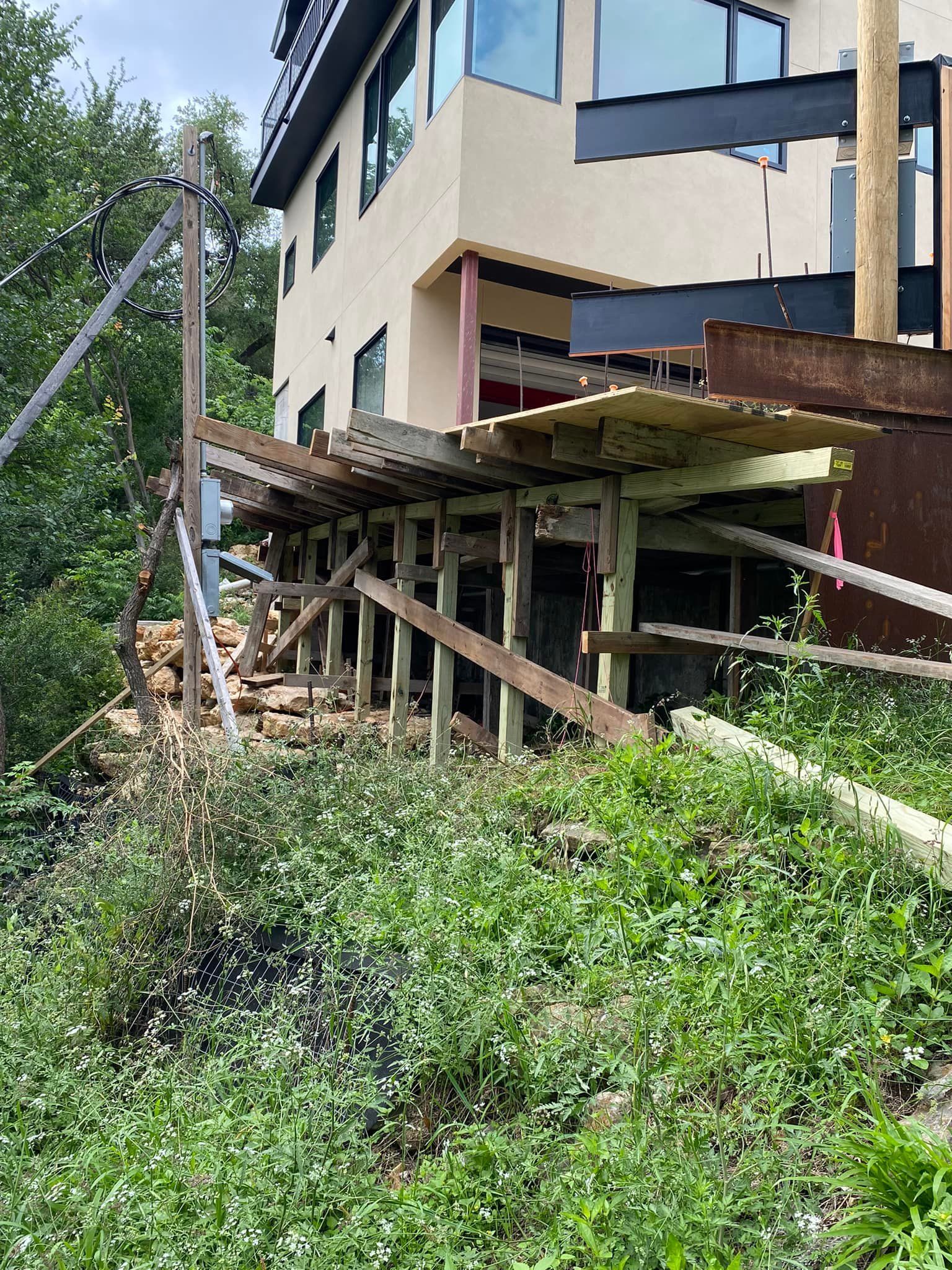 A house is being built on stilts on the side of a hill.