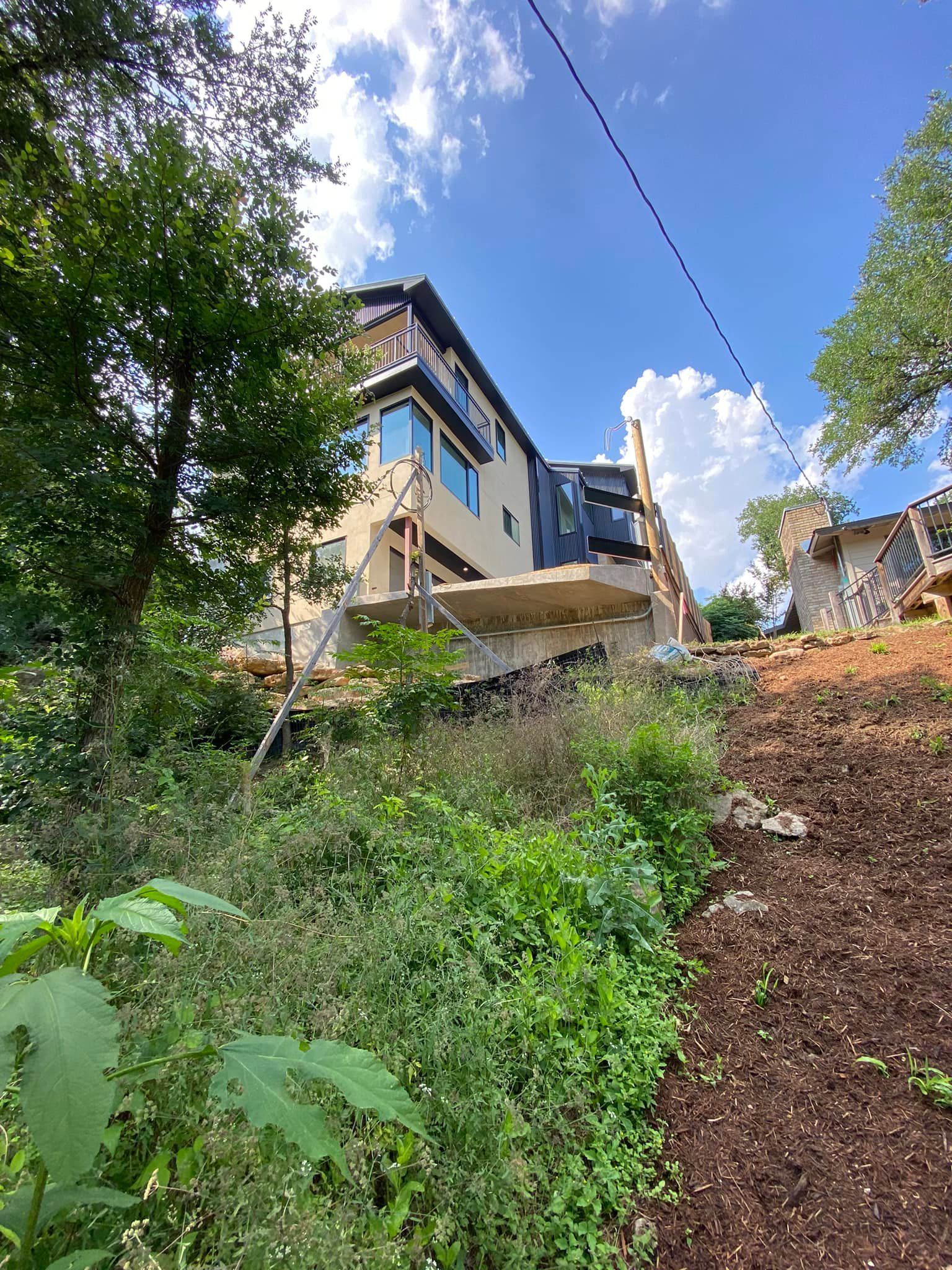 A large house is being built on top of a hill surrounded by trees.