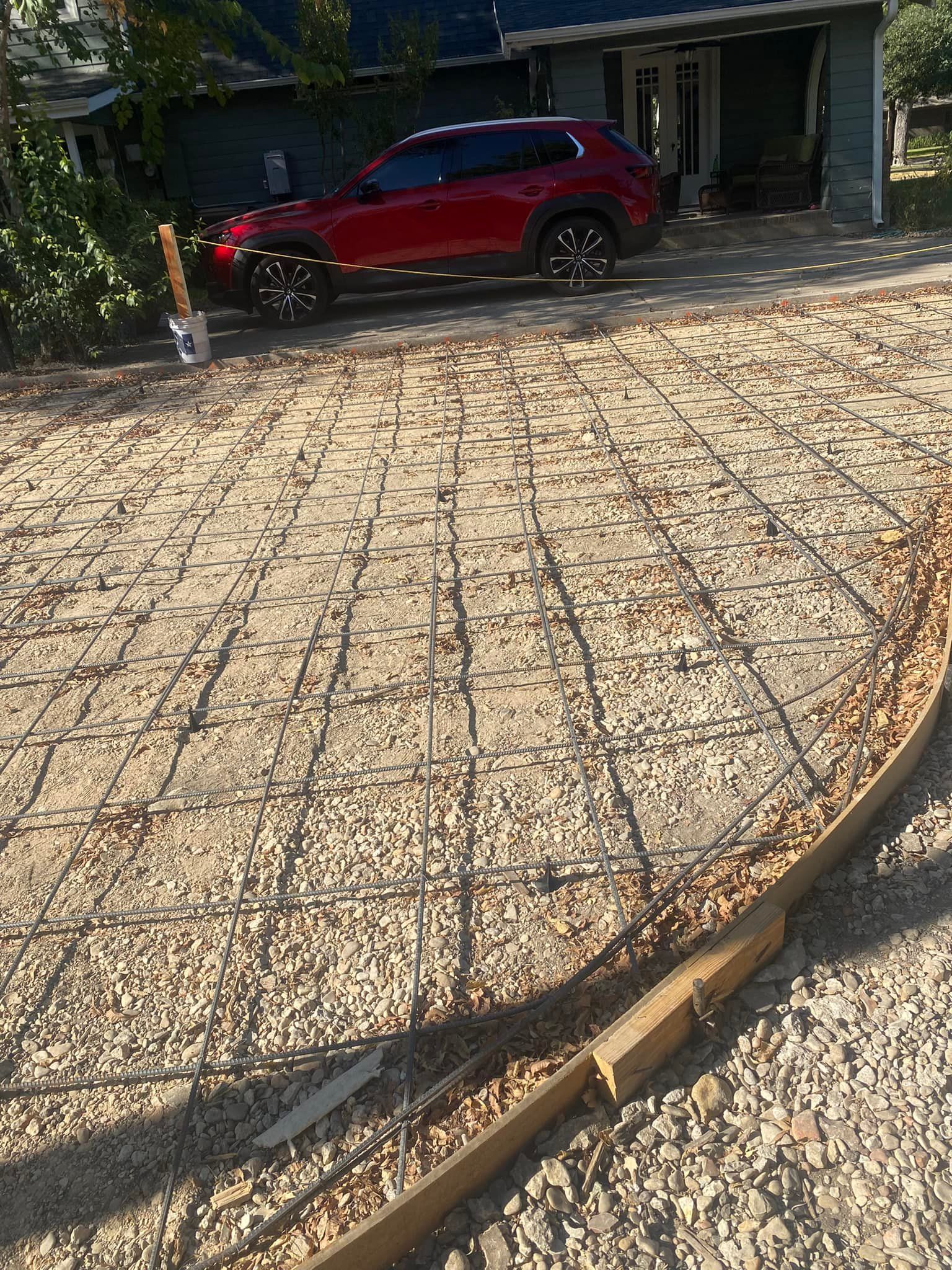 A red car is parked in the driveway of a house.
