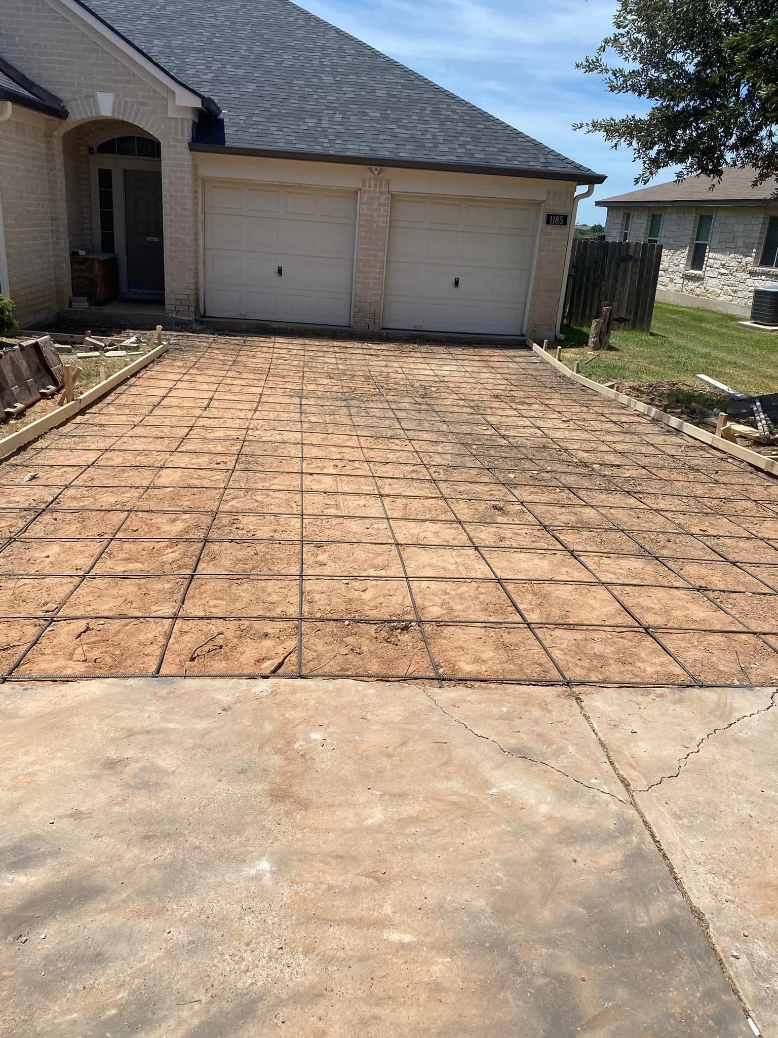 A concrete driveway is being built in front of a house.