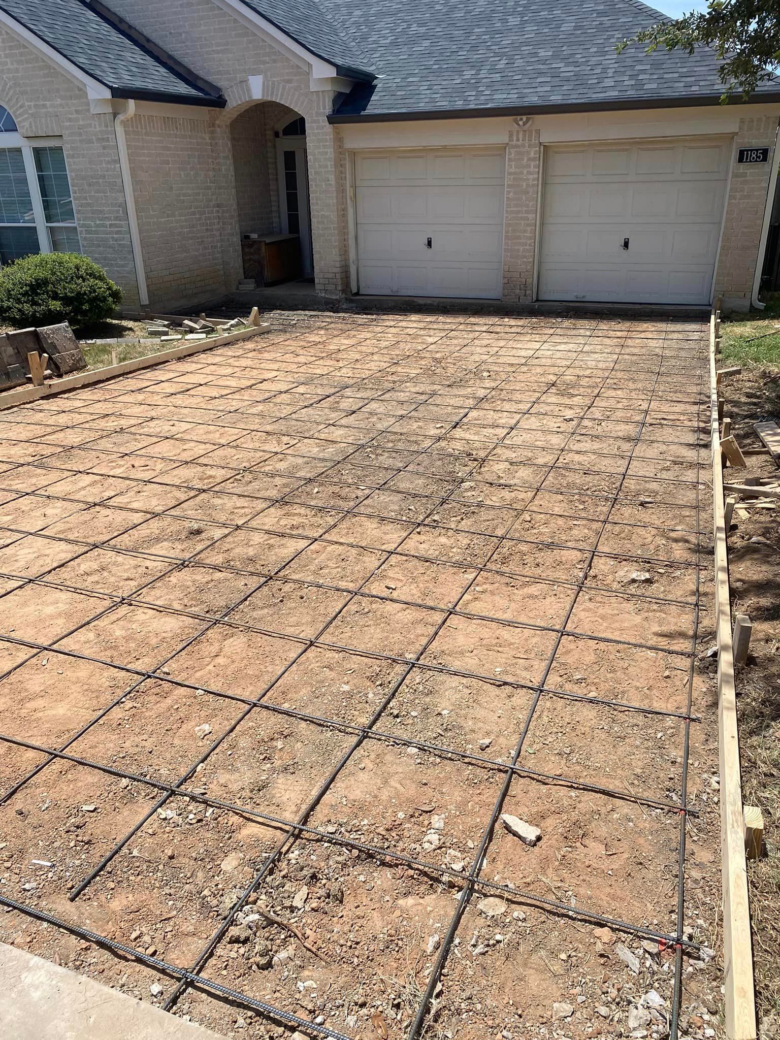 A concrete driveway is being built in front of a house.
