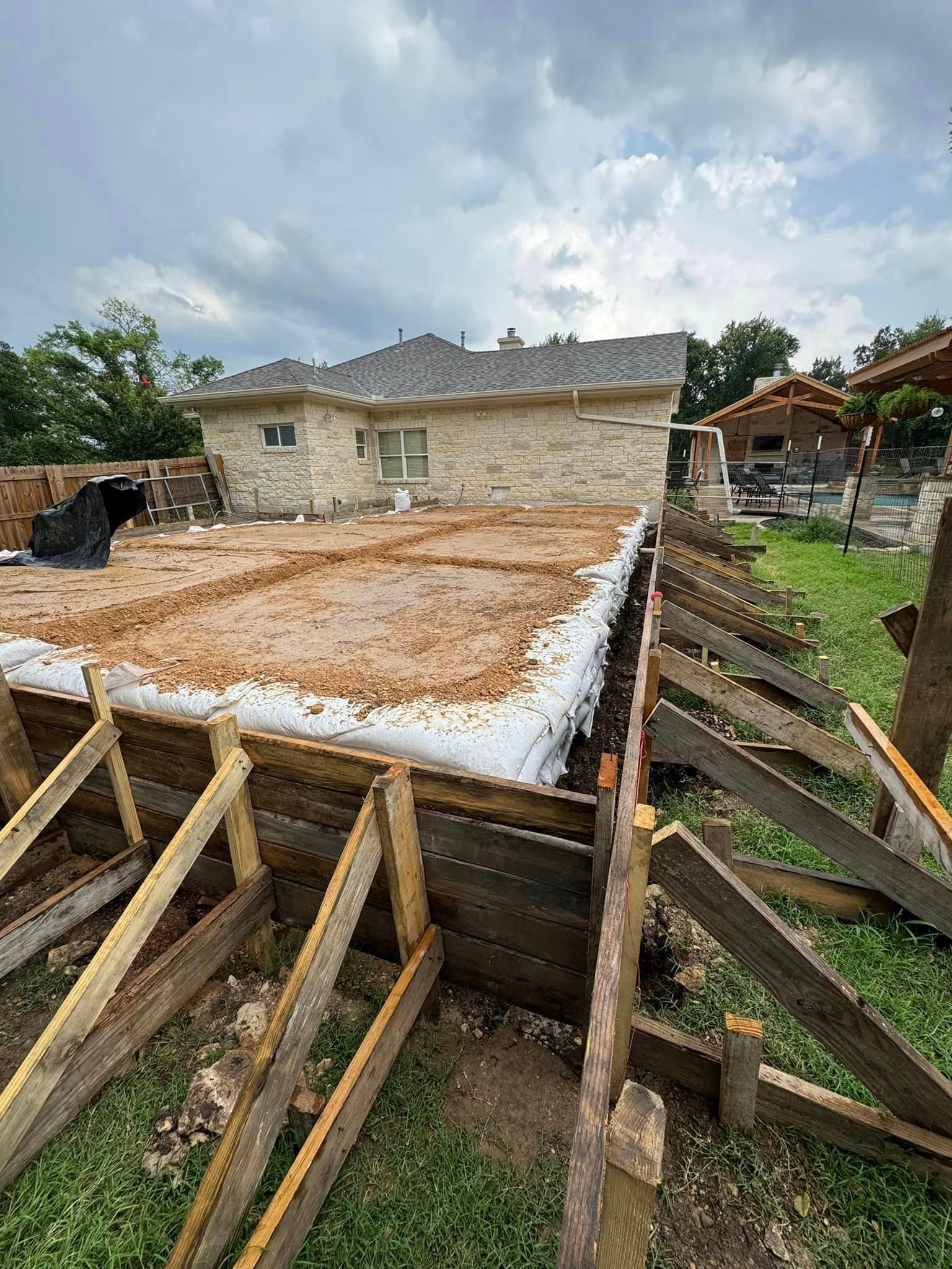The foundation of a house is being built in a backyard.