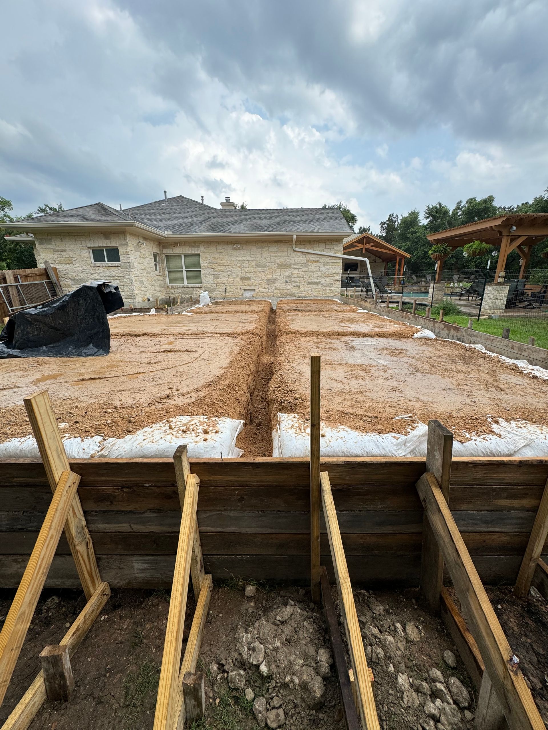 A house is being built on a dirt lot with a wooden foundation.