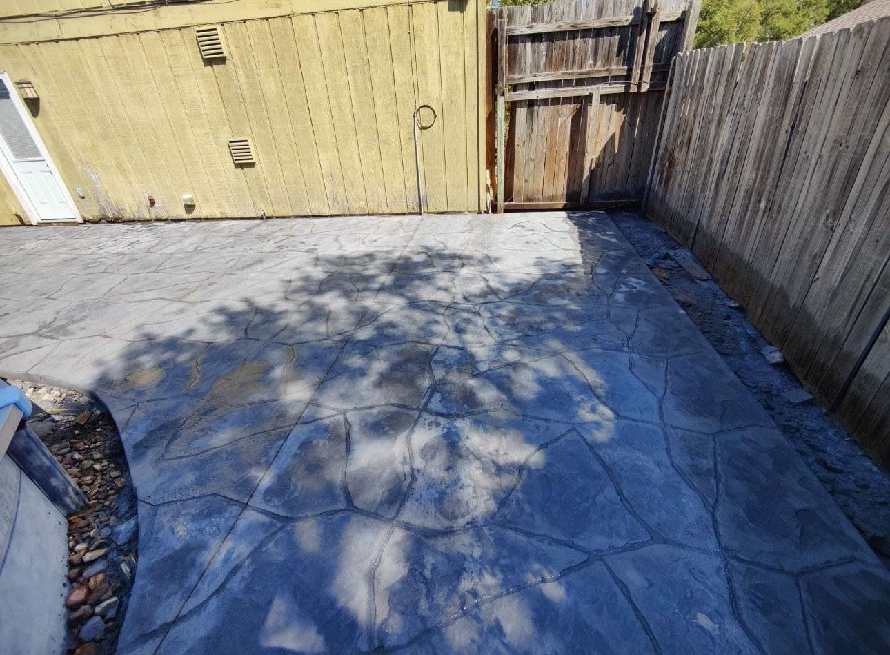A concrete patio with a wooden fence in the background.