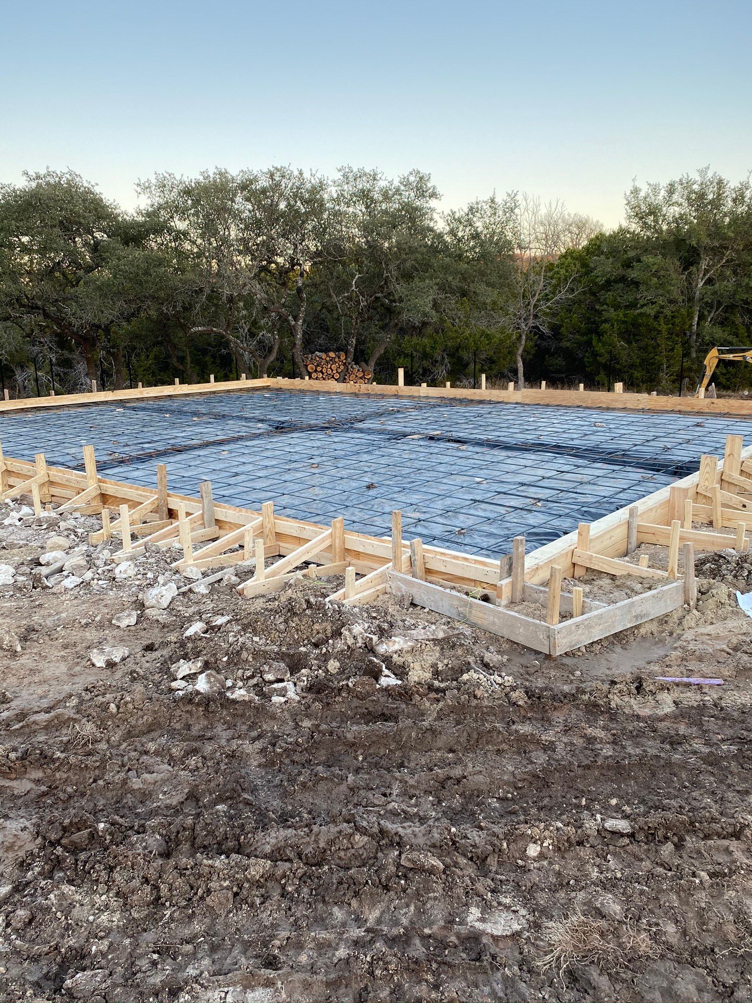 A large pool is being built in the middle of a dirt field.