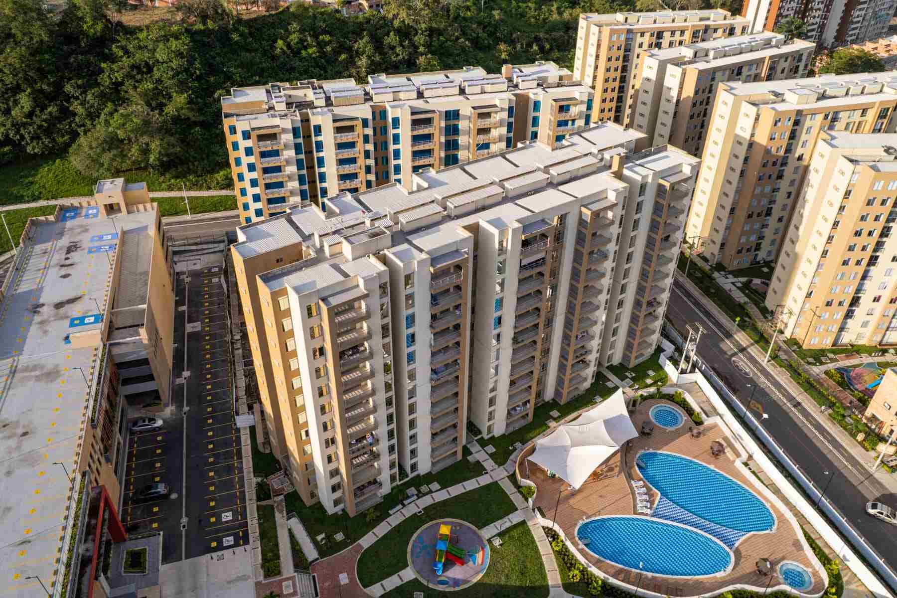 Una vista aérea de un gran complejo de apartamentos con piscina en el medio.