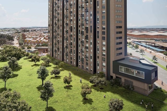 Un edificio grande con muchas ventanas está rodeado de árboles y césped.