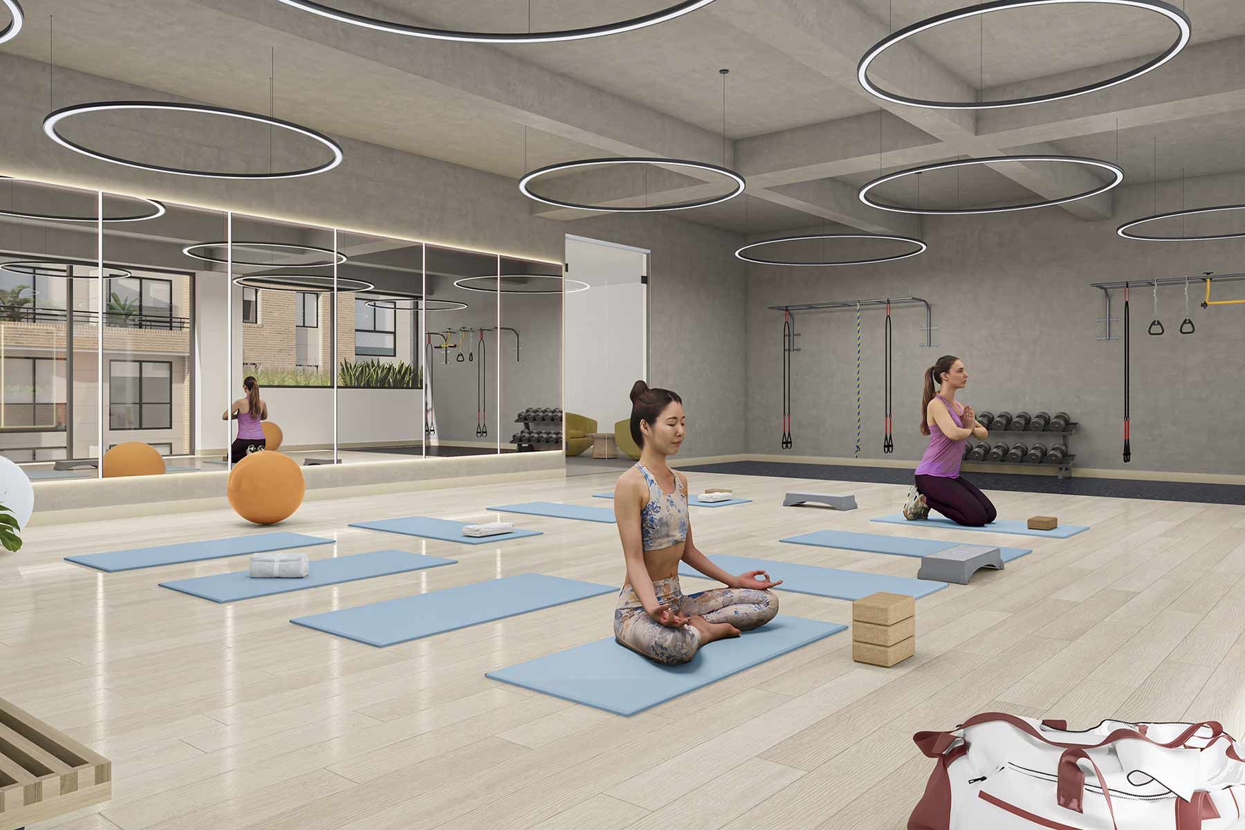 Una mujer está sentada en posición de loto sobre una estera de yoga en un gimnasio.
