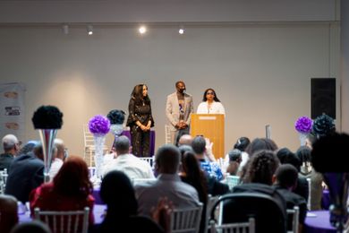 A group of people are sitting at tables in front of a podium.