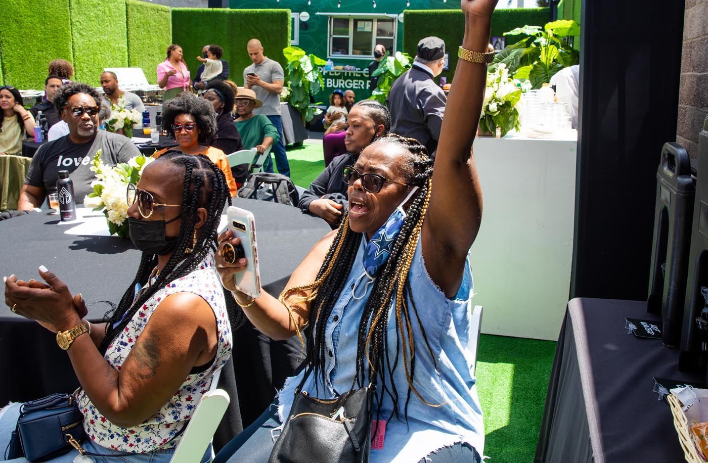 A group of people are sitting at tables with their hands in the air.