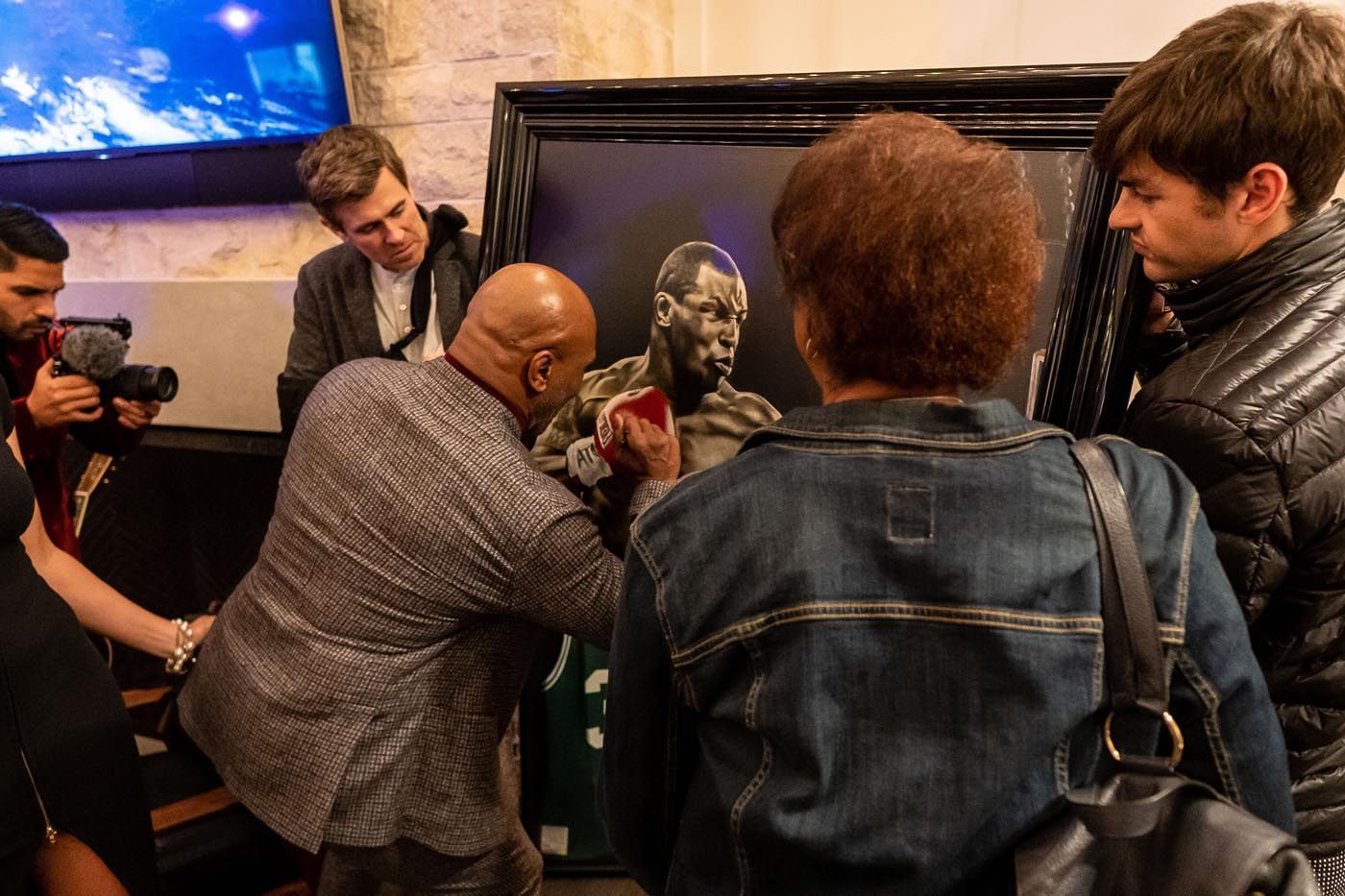 A group of people are looking at a painting of a boxer.