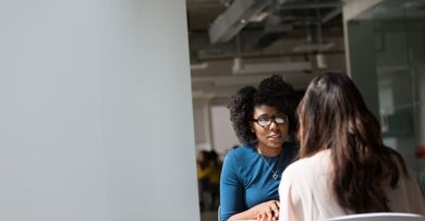 Two women are sitting at a table having a conversation.