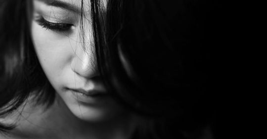 A black and white photo of a woman 's face with her eyes closed.