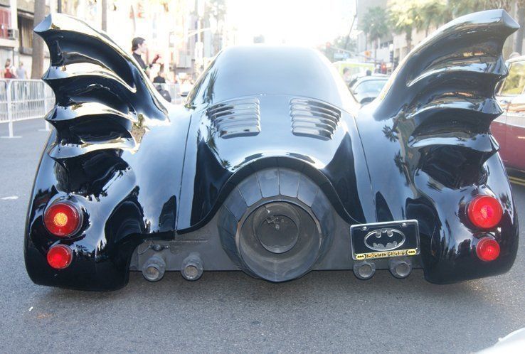 Black Batmobile car, rear view, with wing-like fins and jet engine.